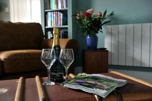 a bottle of champagne and two glasses on a table at Beechurst Serviced Apartments in Cheltenham