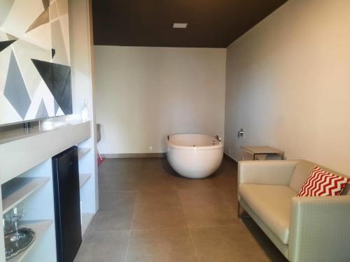 a room with a bath tub and a couch in a room at Capão do Cerrado Pousada e Spa in Itabirito