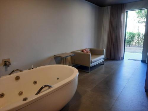 a bathroom with a tub and a chair and a couch at Capão do Cerrado Pousada e Spa in Itabirito