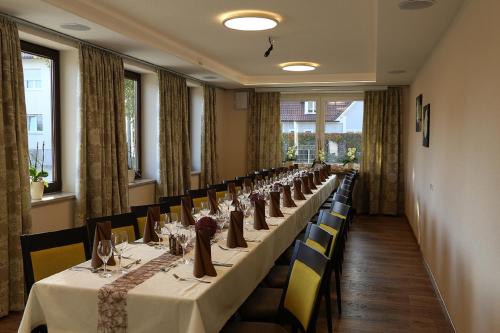 a long row of tables in a room with windows at Zu Müllers Winkelhausen in Langenmosen