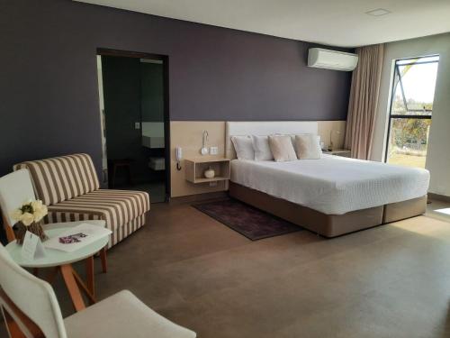 a bedroom with a bed and a couch and a chair at Capão do Cerrado Pousada e Spa in Itabirito