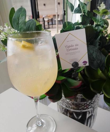 a drink in a glass next to a vase of flowers at Capão do Cerrado Pousada e Spa in Itabirito