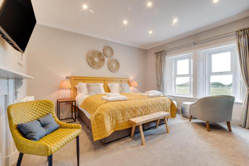 a bedroom with a bed and a chair at Castle View by Coast & Country Stays in Bamburgh