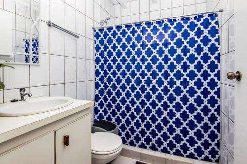 uma casa de banho com um WC e uma cortina de chuveiro azul em CityLife Apartments in Willemstad - groundfloor 2 bedroom apartment - C em Willemstad