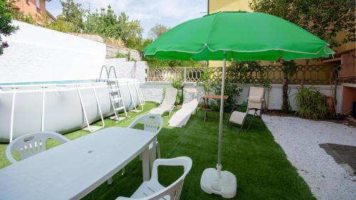 een tafel en stoelen met een groene parasol bij Welcomely - Casa Lisa in Nuoro
