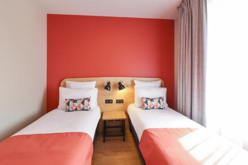 two beds in a room with red walls at Appart'City Confort Toulouse Diagora Labège in Labège