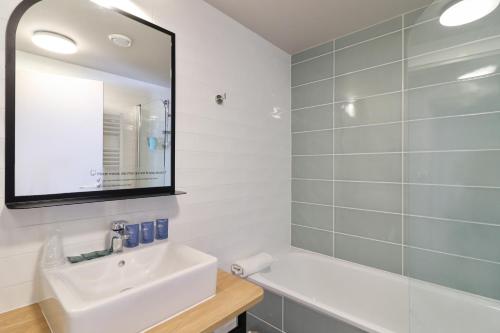 a white bathroom with a sink and a mirror at Appart'City Confort Toulouse Diagora Labège in Labège