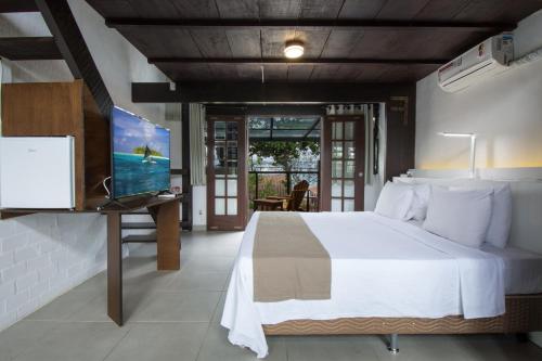 a bedroom with a bed and a flat screen tv at Pousada do Adriano in Búzios