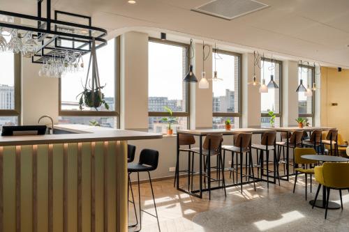 a bar with chairs and tables in a room with windows at B&B HOTEL Antwerpen Centrum in Antwerp