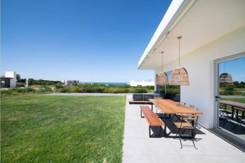 a patio with a table and benches and a field at Casa con vistas al mar con piscina in Porto Covo