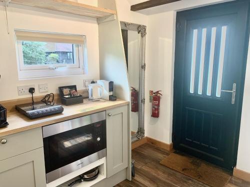 a kitchen with a blue door and a counter with a microwave at Stunning Estate sleeps 22 private parking & garden in Hailsham
