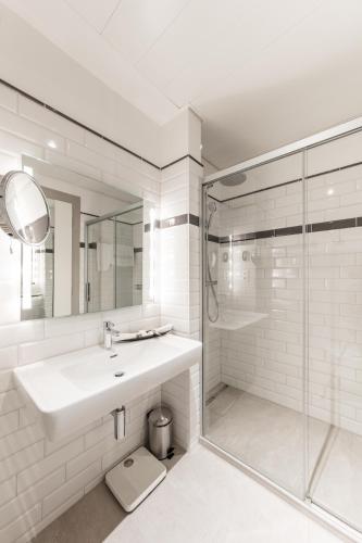 a white bathroom with a sink and a shower at Hotel Victoria in Lausanne