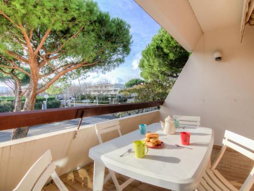 une table et des chaises blanches sur un balcon avec un arbre dans l'établissement Apartment Les Cyprianes-3 by Interhome, à La Grande Motte