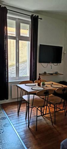 a living room with a table and chairs and a tv at Wimereux 30m2 1 chambre et 1 canapé lit à 2 pas de la plage et du centre in Wimereux