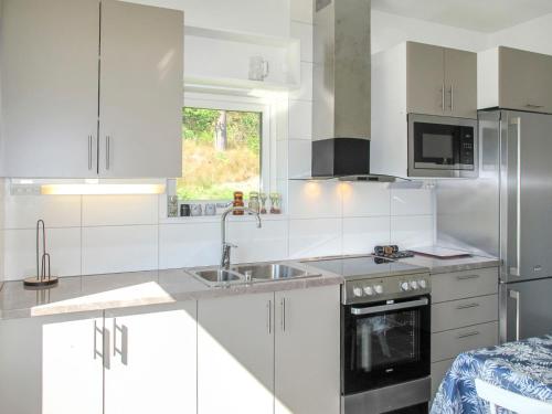 a white kitchen with white cabinets and a sink at Holiday Home Stegeborg Sjöstugan by Interhome in Norrkrog