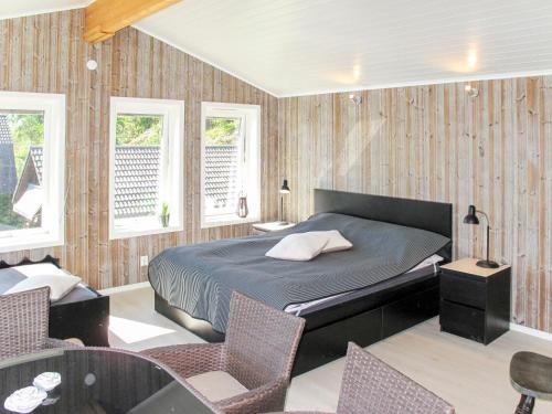 a bedroom with a bed and chairs and windows at Holiday Home Stegeborg Sjöstugan by Interhome in Norrkrog