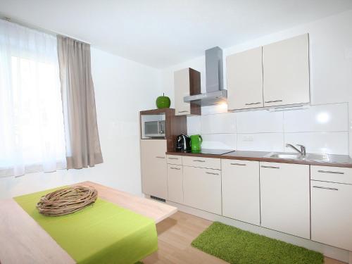 eine Küche mit weißen Schränken und einem grünen Teppich in der Unterkunft Apartment Schaller by Interhome in See