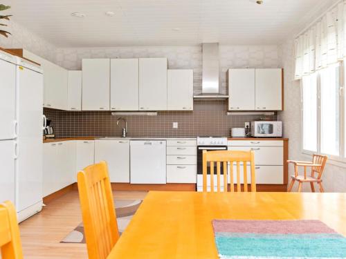KukkolaにあるHoliday Home Nuottiniemi 5 by Interhomeの白いキャビネット、テーブルと椅子付きのキッチンが備わります。