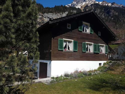 a house with green shuttered windows and a mountain at Apartment Chalet Fluegärtli by Interhome in Gerschnialp