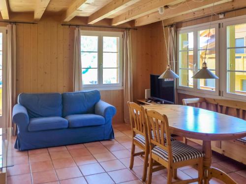 Apartment Chalet Mittelhorn-2 by Interhome في جريندلفالد: غرفة معيشة مع أريكة زرقاء وطاولة