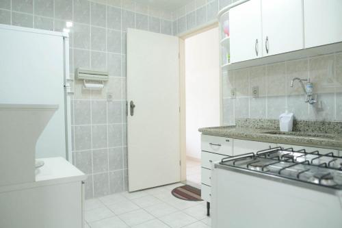 cocina blanca con fregadero y fogones en Ótimo apartamento na Praia dos Castelhanos com Wi-Fi, en Anchieta