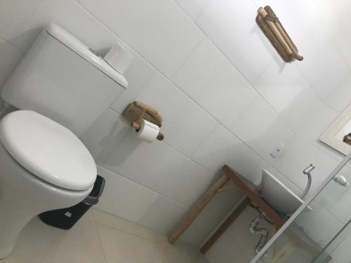 a white bathroom with a toilet and a roll of toilet paper at Residencial Berê in Palhoça