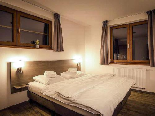 a bedroom with a large white bed with two windows at Holiday Home Residence Lipno-1 by Interhome in Lipno nad Vltavou