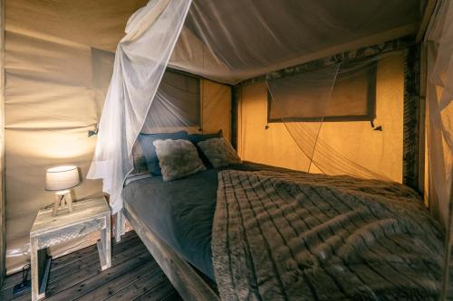 a bedroom with a bed in a tent at Lodges des Grands Chênes in Andelarrot