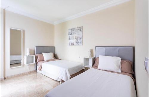 biały pokój z 2 łóżkami i lustrem w obiekcie Apartamento rolycar 103 w mieście Icod de los Vinos
