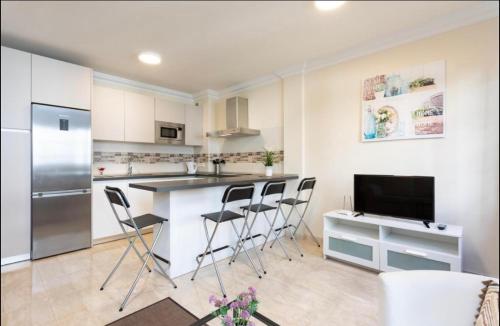 a kitchen with a bar with chairs and a tv at Apartamento rolycar 103 in Icod de los Vinos