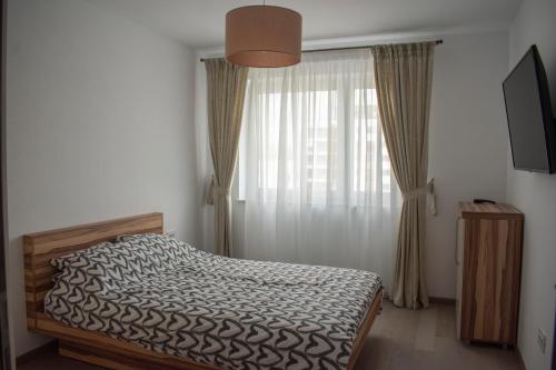a bedroom with a bed and a window with curtains at Tampa View Kasper in Braşov