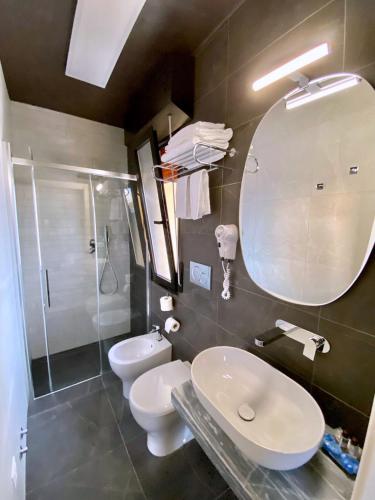 a bathroom with two toilets and a sink and a mirror at Hotel Maioli B&B in Misano Adriatico