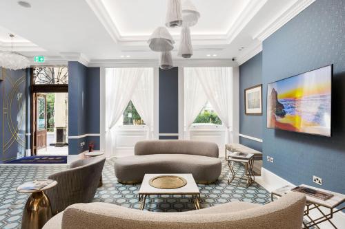 uma sala de estar com paredes e cadeiras azuis em Commodore Hotel em Londres