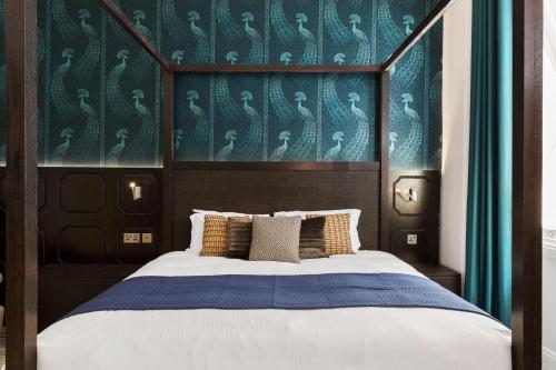a bedroom with a large bed with a blue wall at Commodore Hotel in London