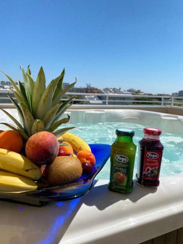 a plate of fruit and juice next to a swimming pool at Hotel Maioli B&B in Misano Adriatico
