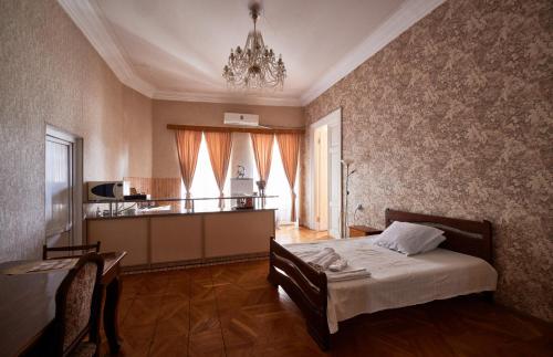 a bedroom with a bed and a kitchen with a chandelier at Apartment Mate in Tbilisi City