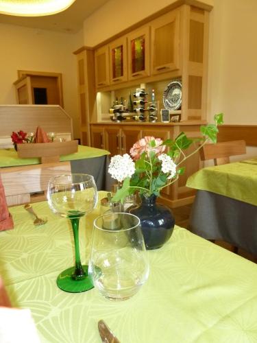 a table with two wine glasses and a vase with flowers at HOTEL RESTAURANT COLLIN in Ferrette