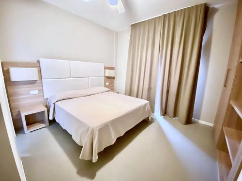 a bedroom with a white bed and a window at Hotel Maioli B&B in Misano Adriatico