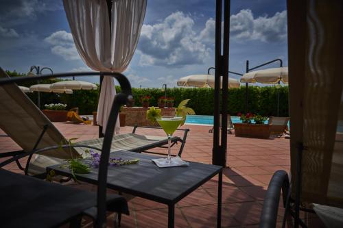 a table with a drink on it next to a pool at Villa Curina Resort in Castelnuovo Berardenga