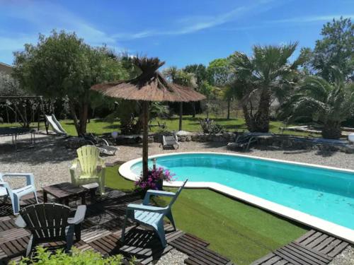 een zwembad met stoelen en een tafel en een parasol bij Chambres d hôtes Chez Valérie et Bernard in Nissan-lez-Enserune