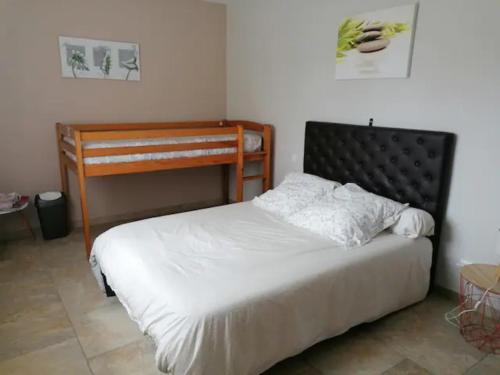 een slaapkamer met een bed met een houten hoofdeinde bij Chambres d hôtes Chez Valérie et Bernard in Nissan-lez-Enserune