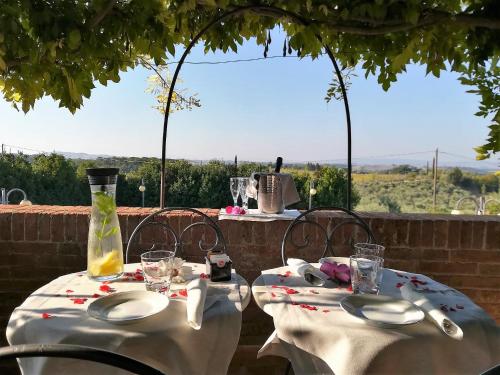 two tables with white plates and a vase on a patio at Villa Curina Resort in Castelnuovo Berardenga