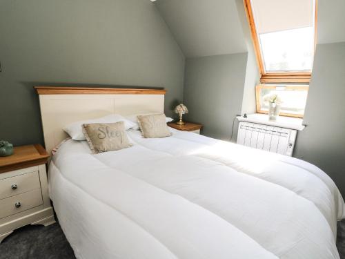 uma grande cama branca num quarto com uma janela em Gorrie's Lair em Spean Bridge