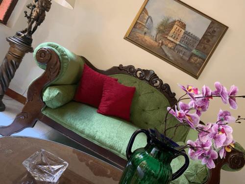 a green couch with red pillows and a table with flowers at Casa Grande in Medellín