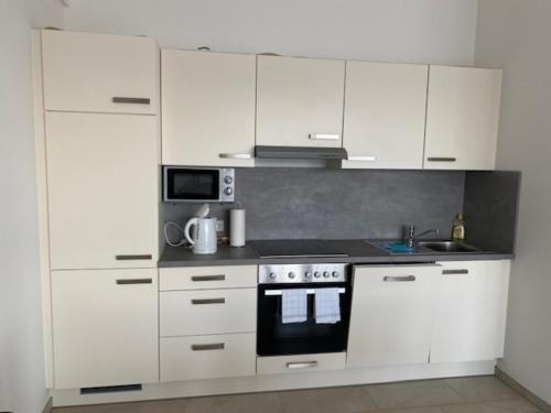 a kitchen with white cabinets and a stove top oven at Appartement 17 in Oerlinghausen