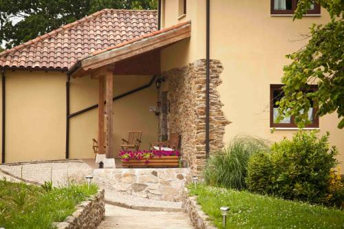 un porche de una casa con una pared de piedra en La Casa de la Abuela Milagros en Pravia