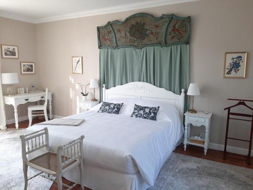 - une chambre avec un grand lit blanc et un bureau dans l'établissement Maison Coqueréaumont, à Montagne