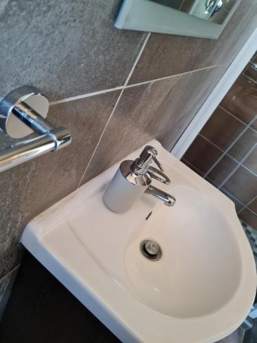 a white bathroom sink with a soap dispenser on it at Village Kulture - Guest House in Rustenburg