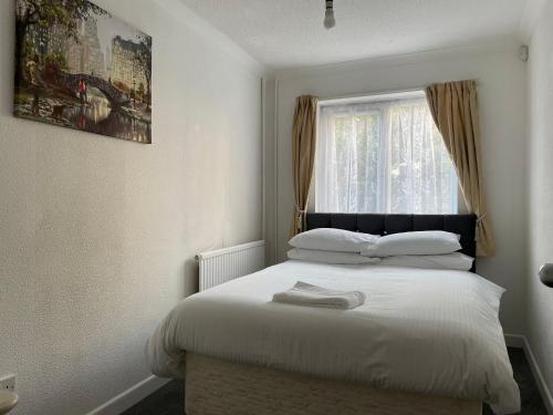 a bedroom with a white bed with a window at Tivoli Bungalow in Weston-super-Mare