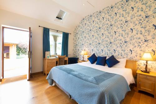a bedroom with a bed with blue and white wallpaper at The Red Lion Hinxton in Hinxton